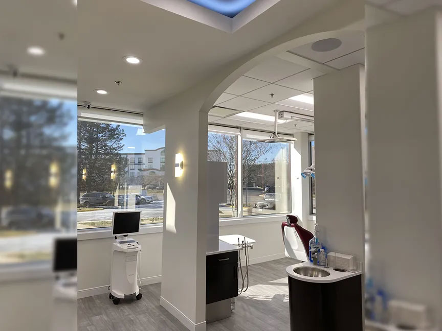 A modern dental office interior with a large skylight, white walls, and sleek furnishings.