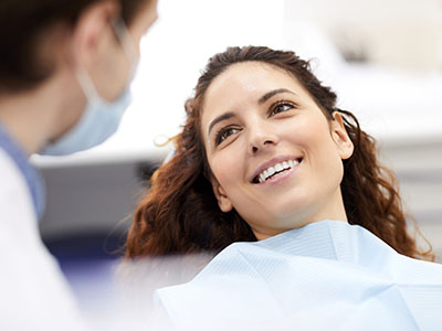Woman in dentist s chair smiling at camera, with dental professional standing behind her.