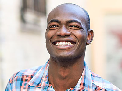 A smiling man with short hair, wearing a plaid shirt.