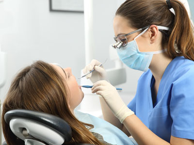 The image features a dental office setting with a woman receiving treatment from a dentist, who is performing a procedure on her teeth.