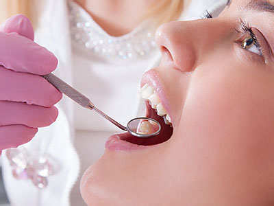 The image shows a person receiving dental care, with a dental professional using a tool to work on their teeth.