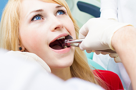 A woman receiving dental care, with a dental professional performing a procedure and the patient wearing protective eyewear.