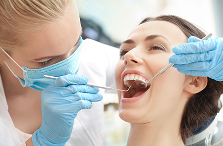 A dental hygienist performing a teeth cleaning procedure on a patient in a dental office.