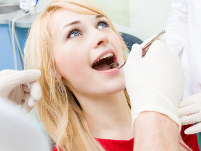 The image depicts a woman in a dental chair receiving dental care, with a dentist performing a procedure on her teeth.