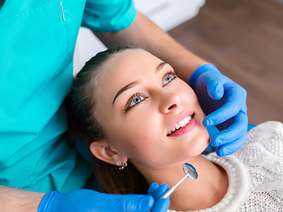 The image depicts a woman receiving dental care, with a dentist performing a procedure on her teeth.